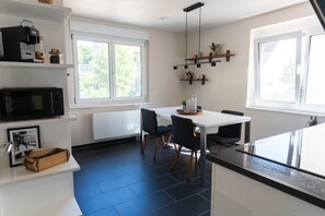 A modern kitchen with a white countertop, black chairs, and a dining table. - 100 m² · up to 6 guests · 3 bedrooms · 8 km from Bamberg (Kemmern)