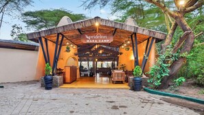 A rustic lodge entrance with a covered porch, a signboard, and outdoor seating. - Azure Mara Haven (Maasai Mara)