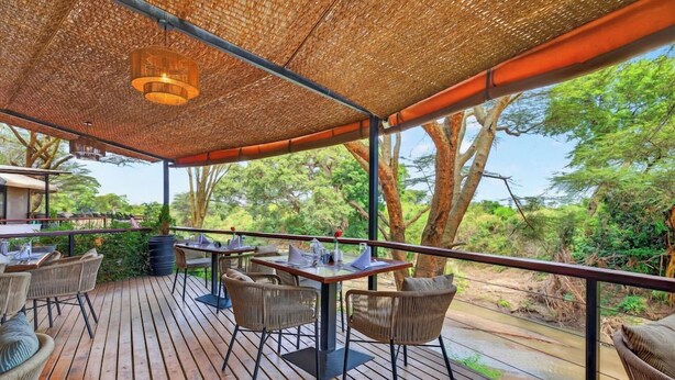 An outdoor dining area with tables and chairs, surrounded by a wooden deck and a woven canopy. - Azure Mara Haven (Maasai Mara)