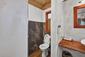 Une salle de bain avec des toilettes blanches, un meuble-lavabo en bois, un miroir et un espace douche.