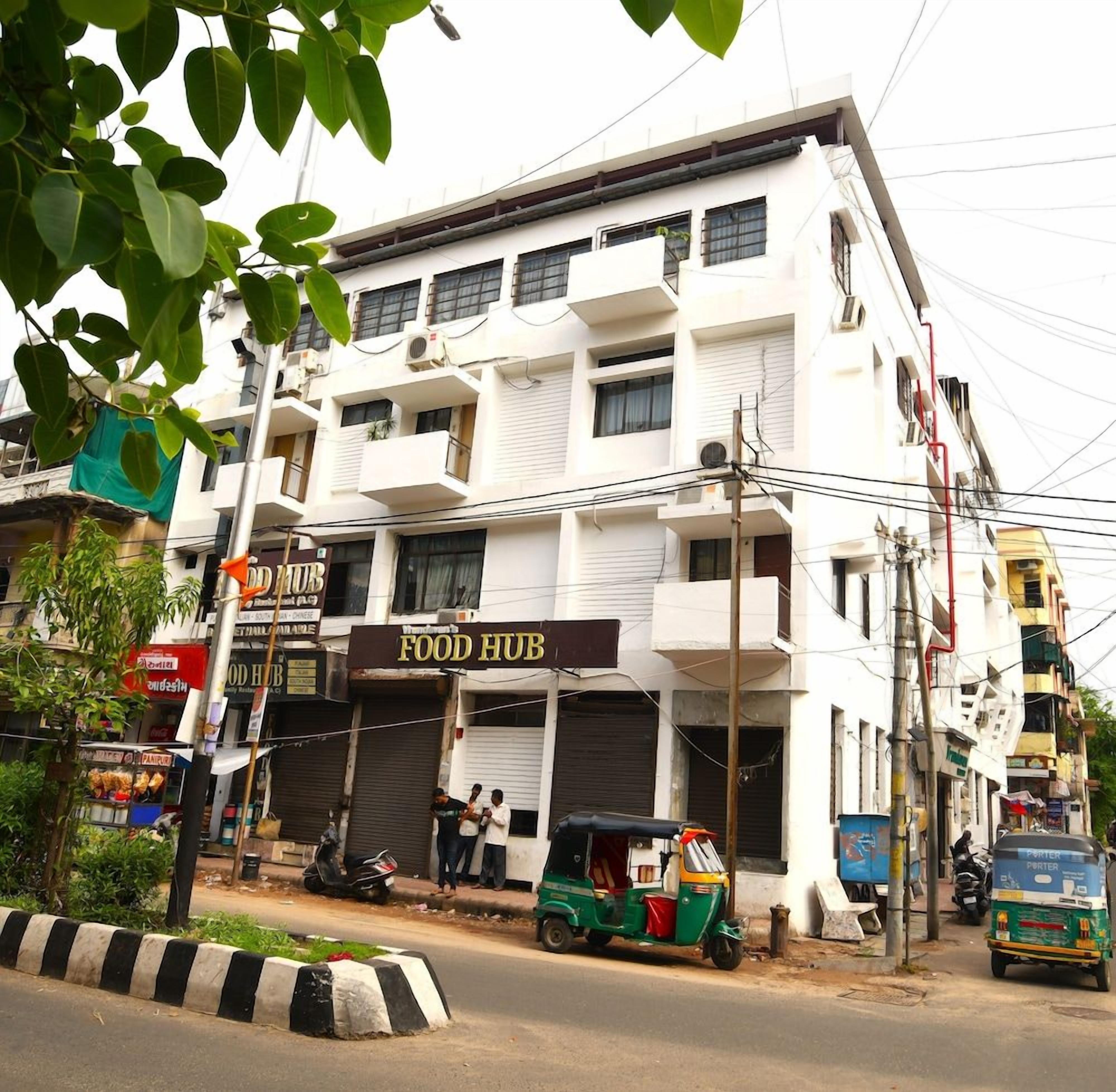 A multi-story building with a sign for a food hub on the ground floor.