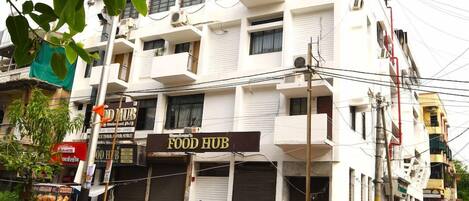A multi-story building with a sign for a food hub on the ground floor.