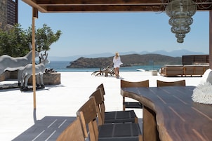 Una terraza con vistas al mar, mobiliario exterior y una escultura de burros.