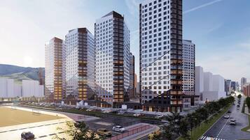 Een modern complex van hoge gebouwen met meerdere woontorens, een parkeerplaats en een weg met voertuigen.