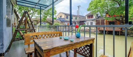 Una mesa de madera con bancos y un florero, frente a un muro de cristal con vista al río.