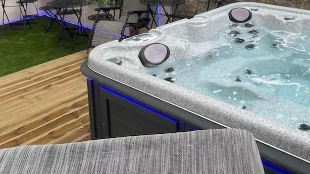 Un jacuzzi con cubierta de madera y mobiliario exterior.