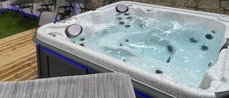 A hot tub with jets, surrounded by outdoor furniture and plants.