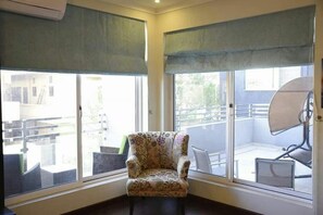 A corner room with a patterned armchair, large windows with blinds, and a satellite dish. - Serene Residence (Islamabad)