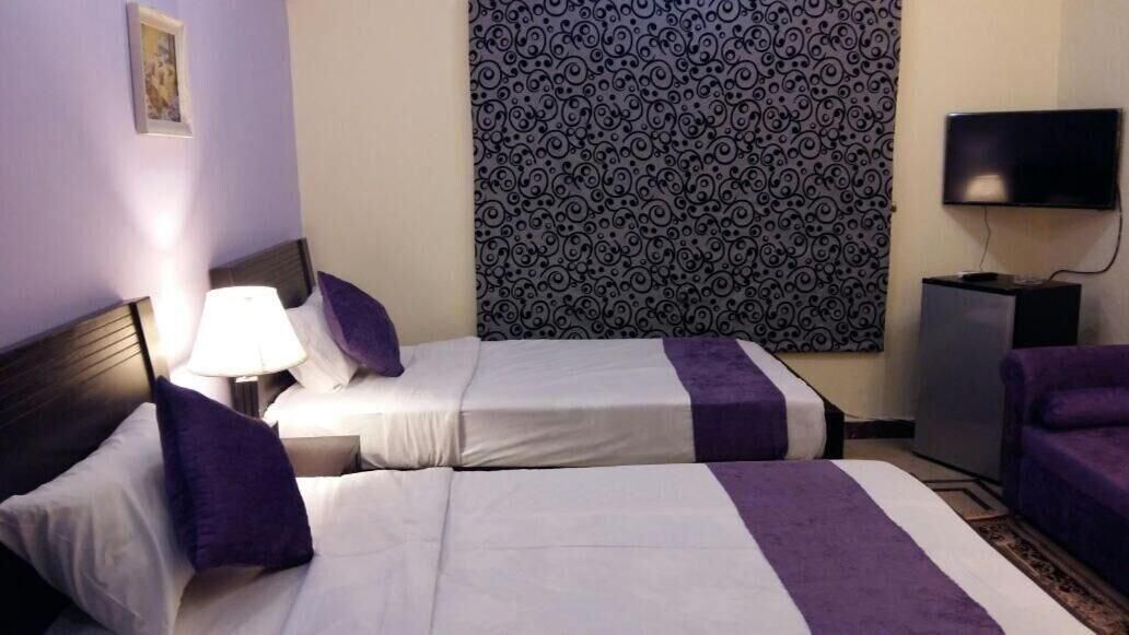 A hotel room with two beds, a TV, and a patterned curtain.