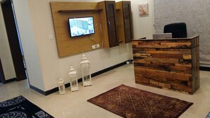 A reception area with a wooden desk, a mounted television, and decorative lanterns. - Serene Residence (Islamabad)