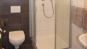 A modern bathroom with a glass-enclosed shower, a toilet, and a sink. - Apartment Elisa (Kaprun)