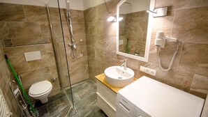 Un baño moderno con ducha envuelta en vidrio, inodoro, lavamanos y espejo.