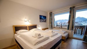 Habitación de hotel con dos camas, un ventanal con vistas a la montaña y un cuadro en la pared.