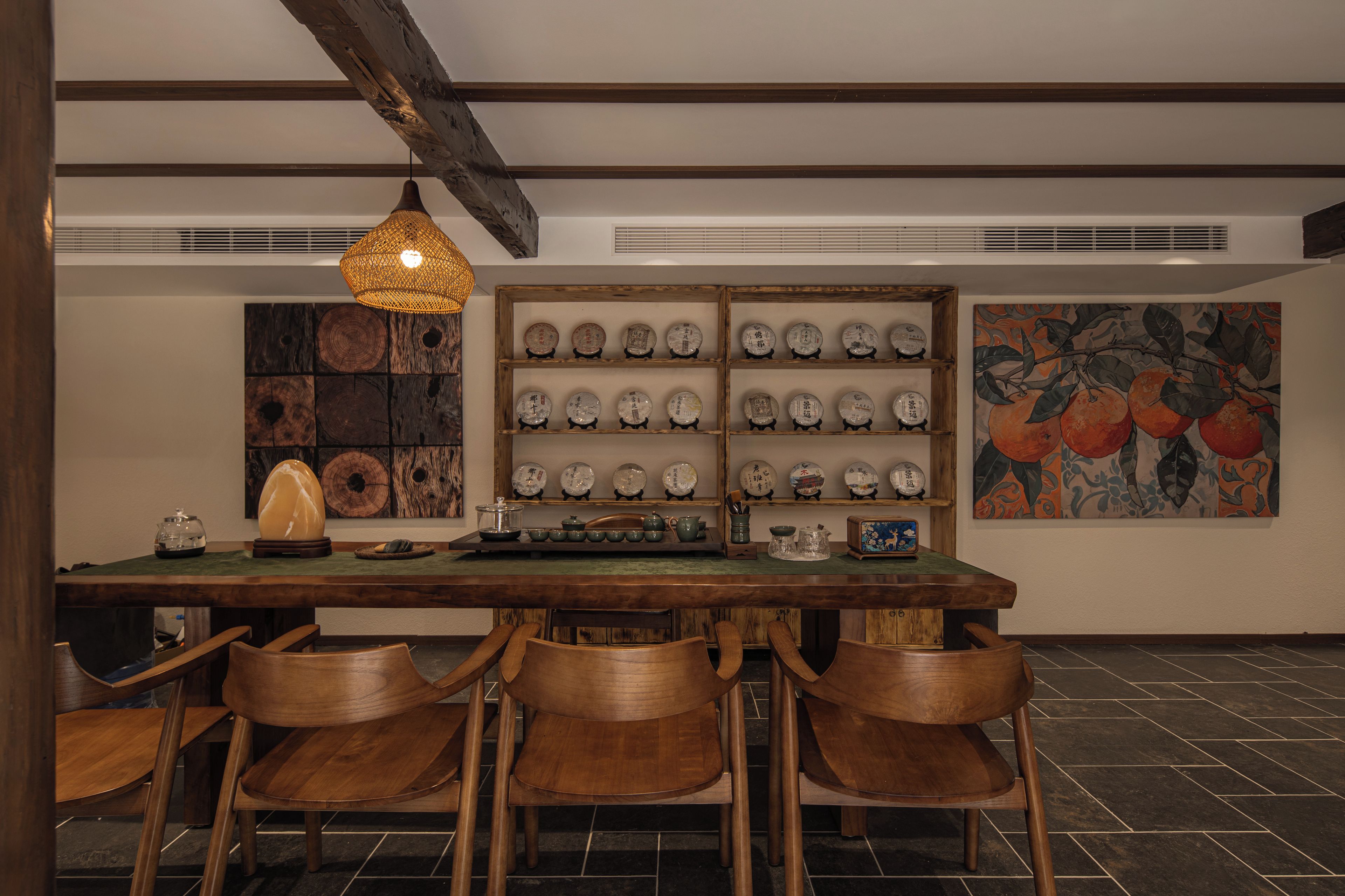 A dining area with a wooden table, chairs, a hanging light fixture, and a wall display of plates.
