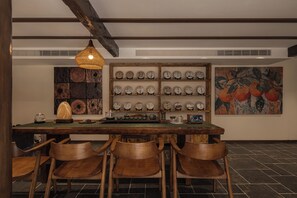 Un comedor con una mesa de madera, sillas, una lámpara colgante y una vitrina con platos.
