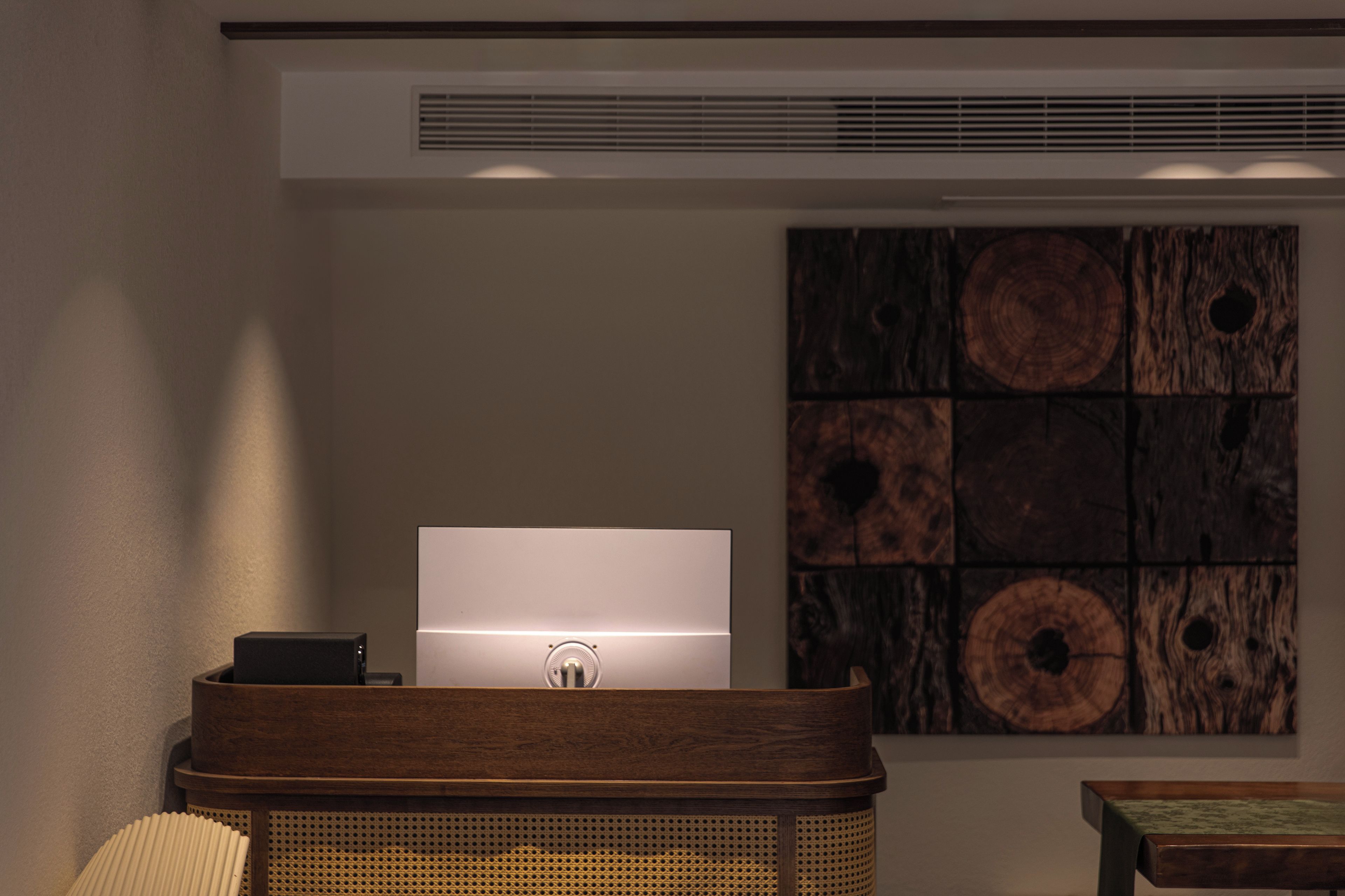 Una habitación con escritorio, silla, lámpara y un panel de madera en la pared.