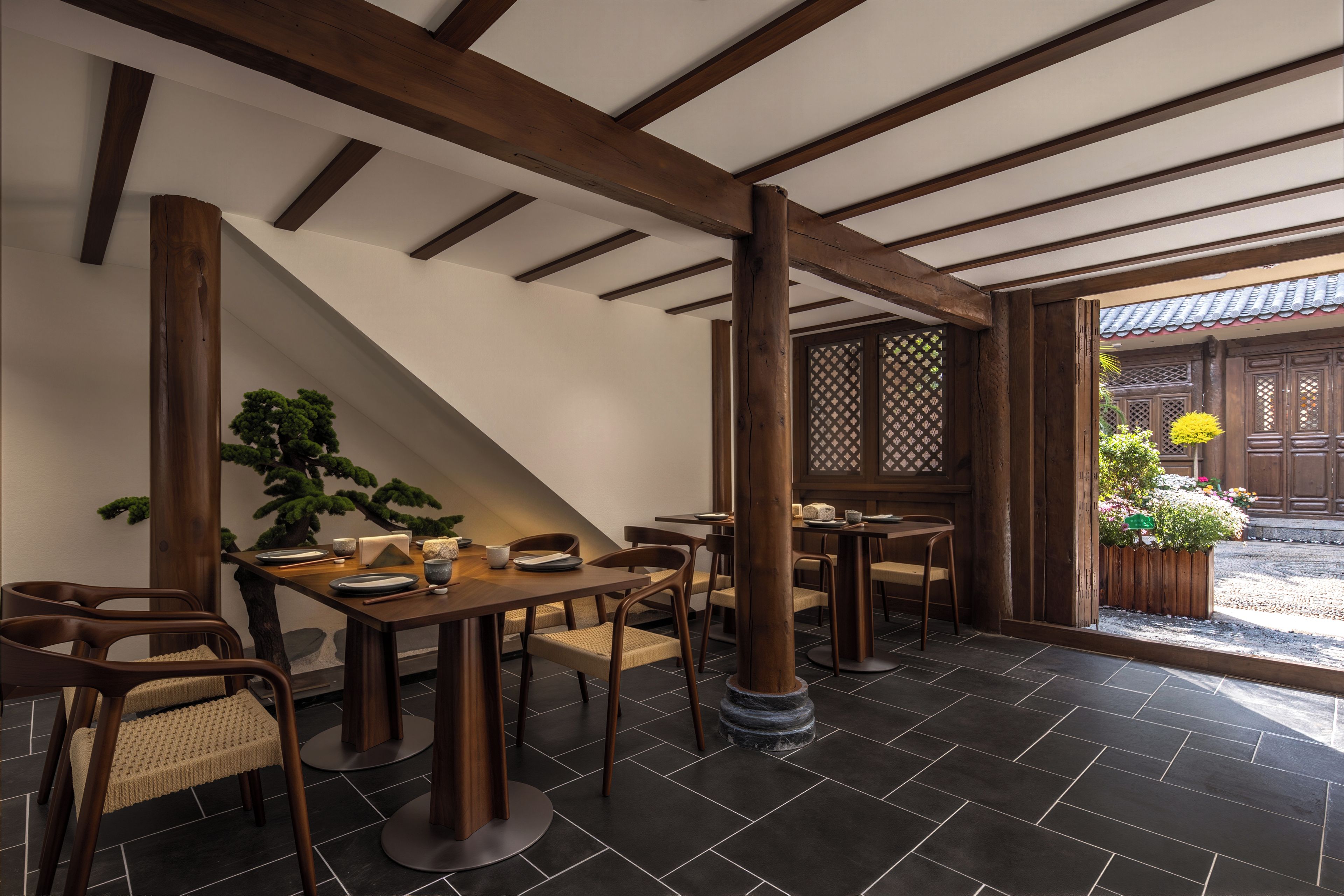 A traditional Japanese-style dining area with tatami mats, wooden furniture, and a view of a garden.