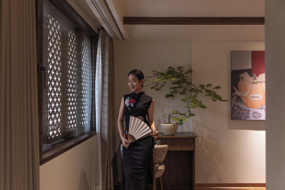 Una persona de pie en una habitación con un tradicional fusuma japonés, una planta en maceta y una obra de arte colgada en la pared.