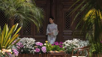 A person standing in front of a wooden structure with intricate carvings, holding a fan.