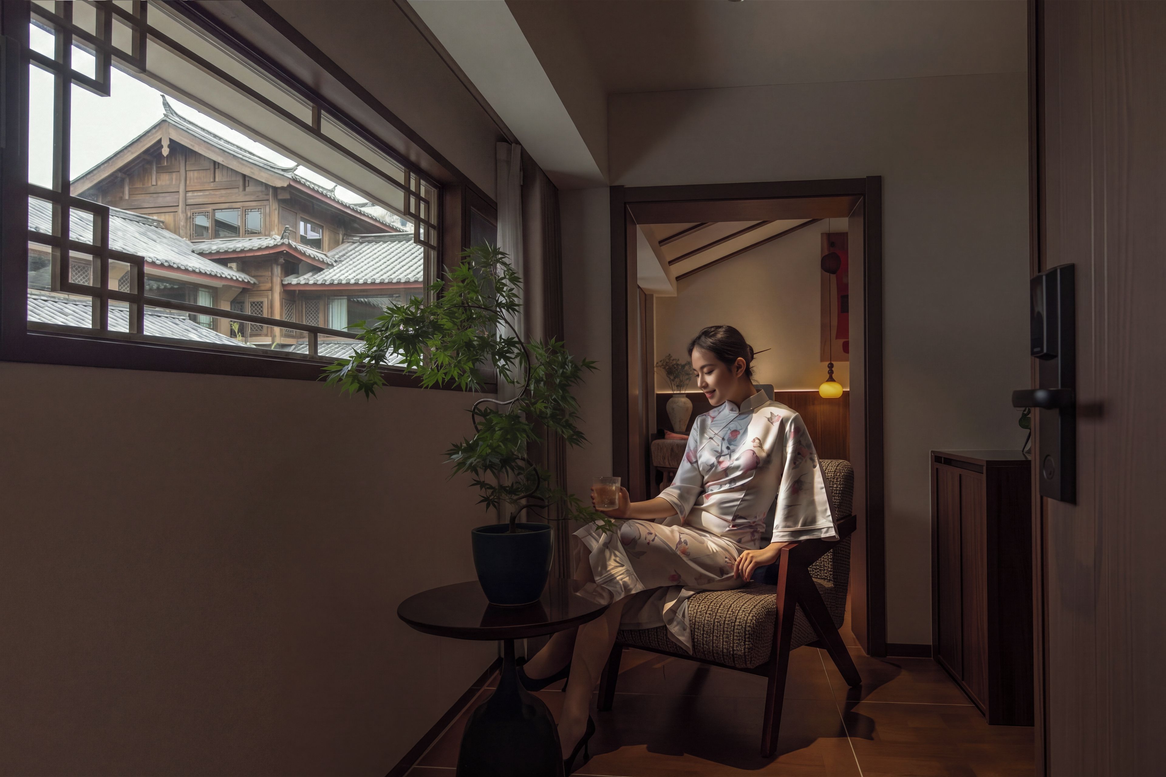 A room with a traditional Japanese-style interior, a potted plant, and a view of traditional buildings outside.