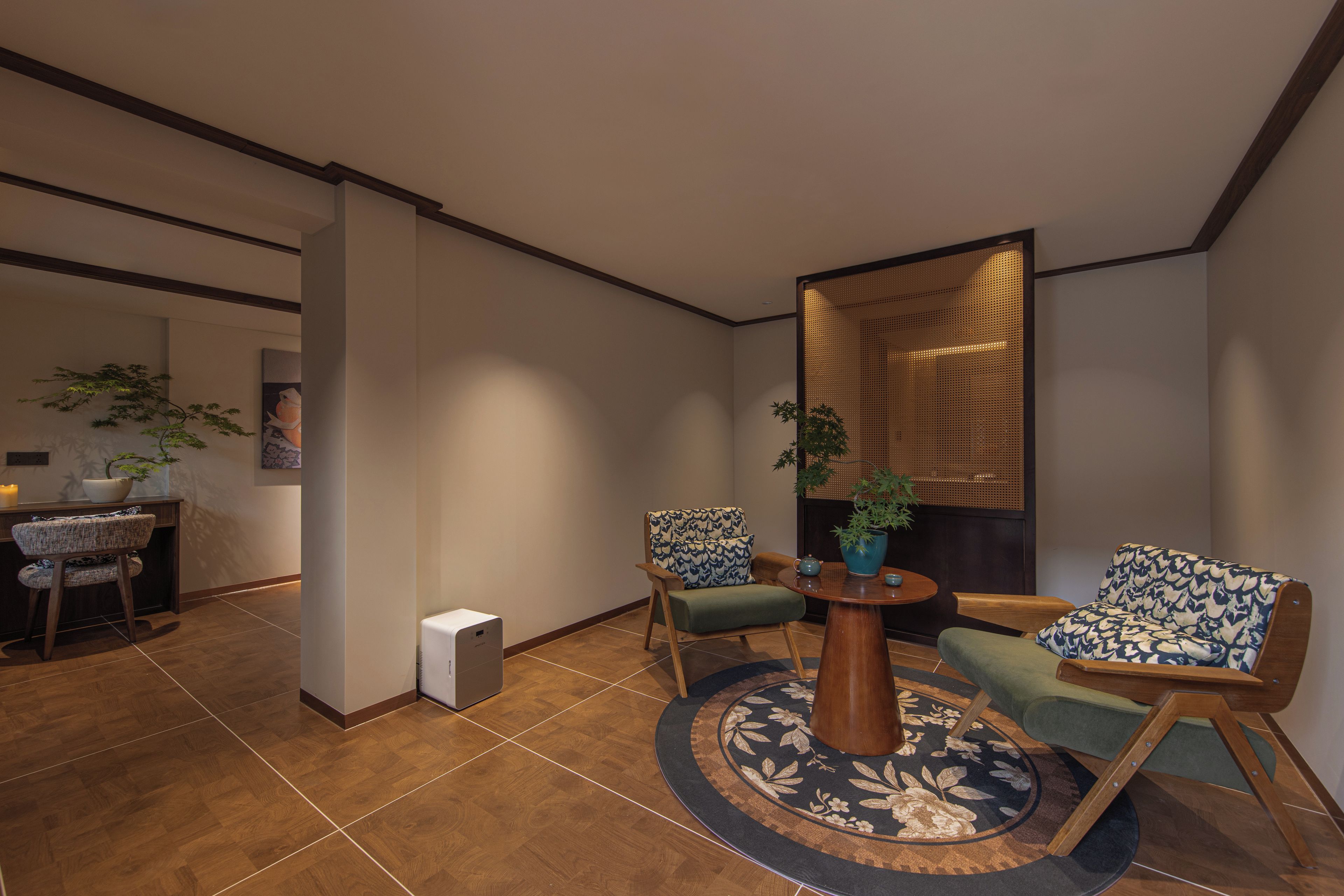 Een moderne woonkamer met een ronde salontafel, twee fauteuils met een patroon, een klein bijzettafeltje en een decoratieve ruimteverdeling.