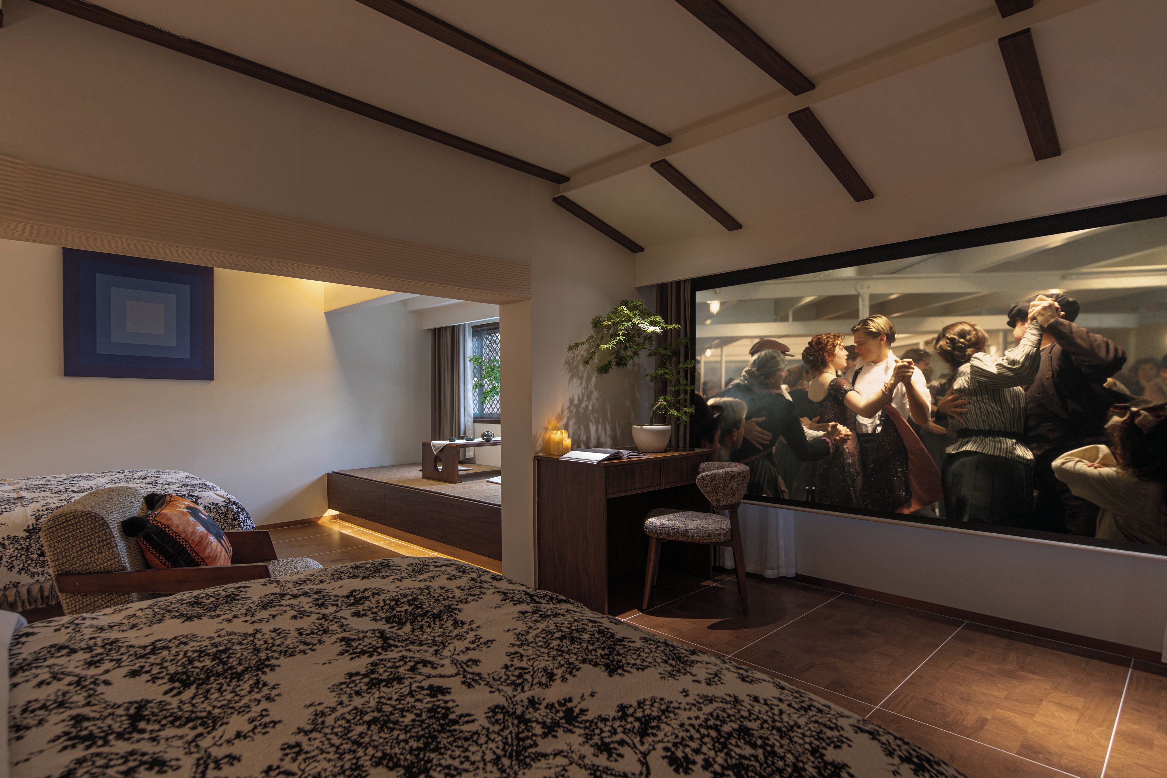 A modern bedroom with a large bed, a desk, and a large mirror reflecting a room scene.