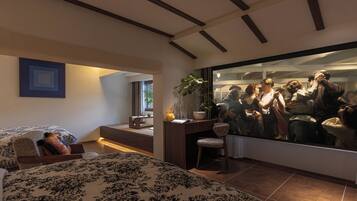 A modern bedroom with a large bed, a desk, and a large mirror reflecting a room scene.
