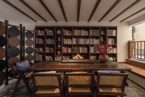 Una habitación amplia con una gran mesa de madera, sillas de mimbre y una estantería llena de libros.