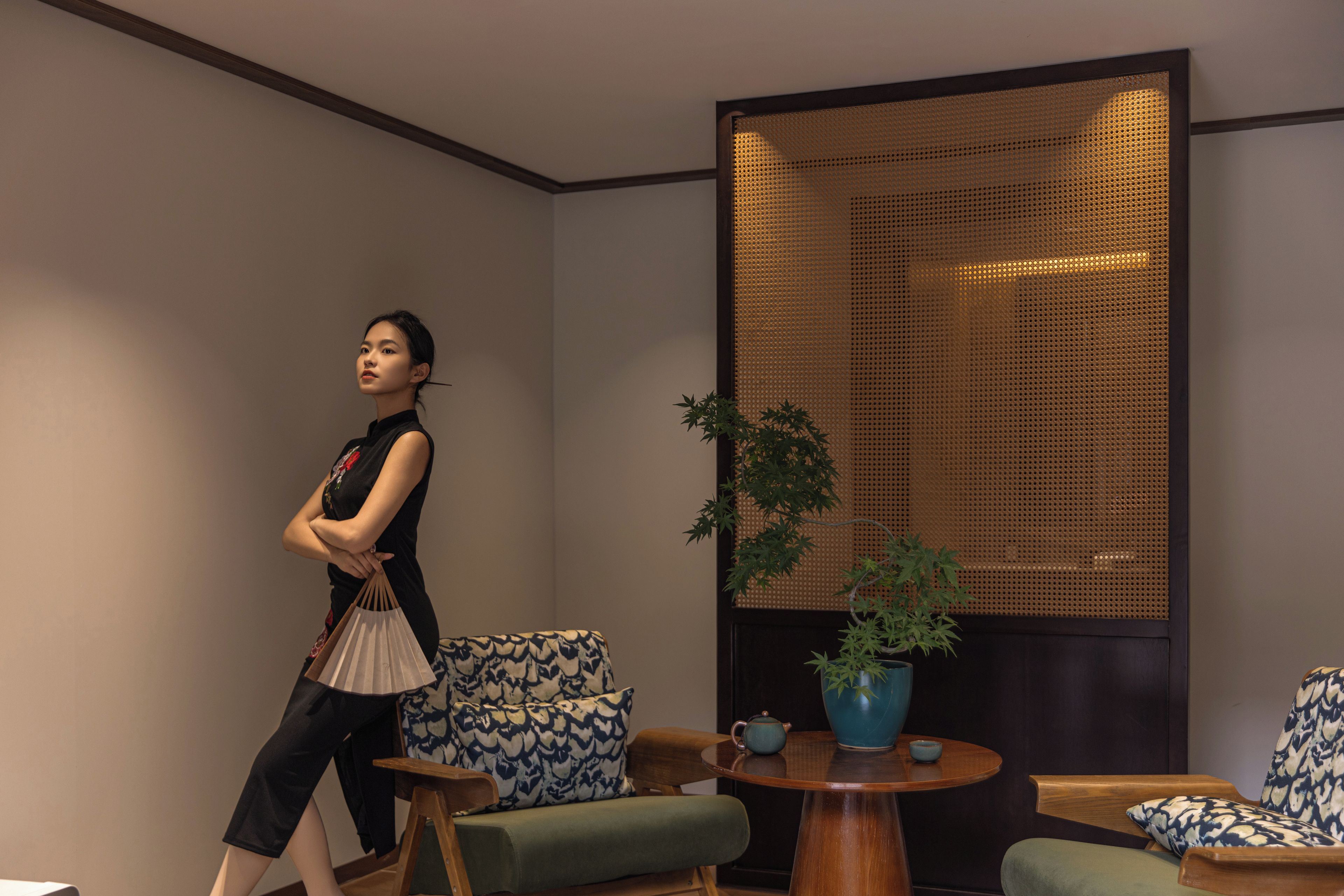 A modern interior with a sofa, a round wooden table, and a decorative wall panel.