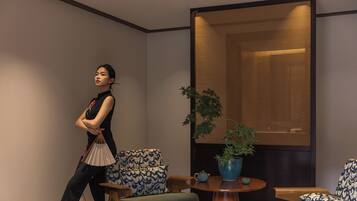 A modern interior with a sofa, a round wooden table, and a decorative wall panel.