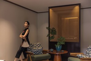 Un interior moderno con un sofá, una mesa redonda de madera y un panel decorativo en la pared.