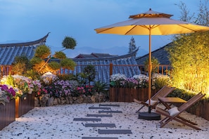 A traditional courtyard with a tiled roof, a wooden fence, and a seating area with a chair and an umbrella. - The Timber Courtyard - Lijiang Old Town - A Preserved Heritage Residence near Mufu Palace (Lijiang)