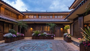 A traditional courtyard with tiled roofs, wooden gates, and flower planters.