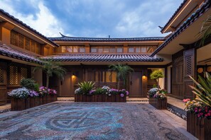 Un patio tradicional con techos de tejas, puertas de madera y macetas con flores.