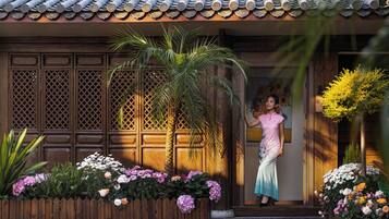 A traditional building with a tiled roof, wooden doors, and a wooden fence with flowers.
