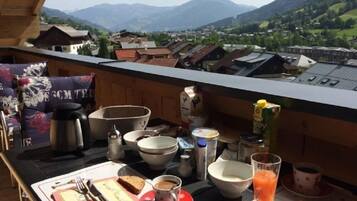Ein Balkon mit Frühstückstisch, mit Blick auf eine Berglandschaft.