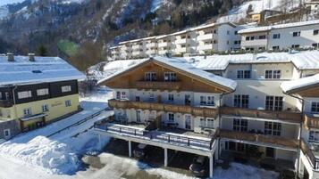 Ein mehrstöckiges Hotel mit Balkonen, einem überdachten Parkplatz und einer Bergkulisse.
