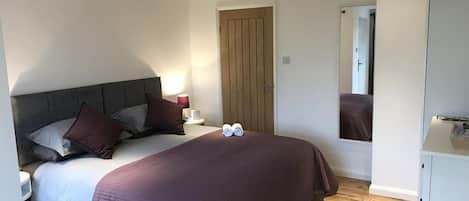 A bedroom with a bed, bedside table, and a mirror.
