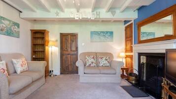 A living room with two sofas, a fireplace, a television, and a ceiling with a name sign.