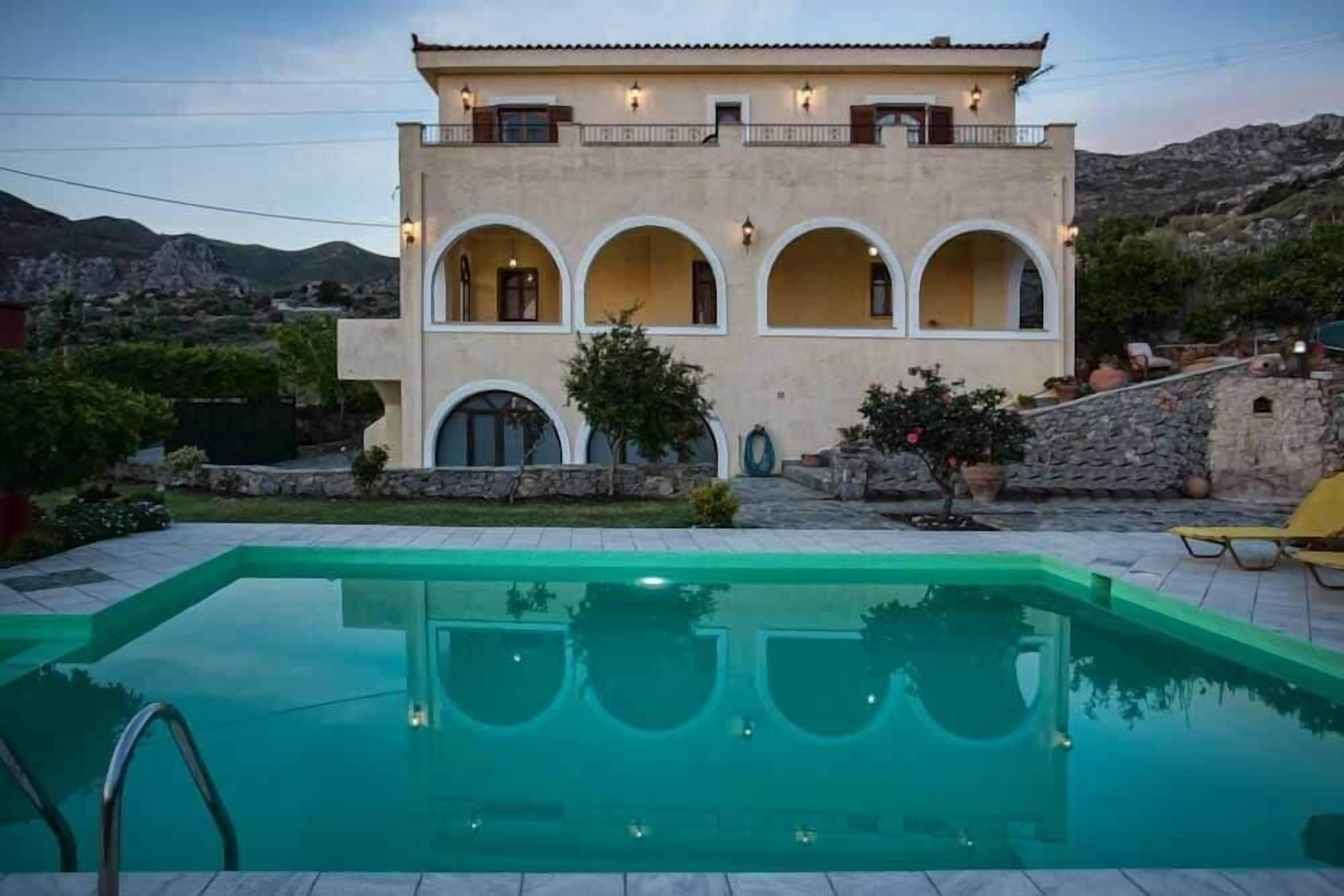 Edifici de dues plantes amb una piscina al primer terme.
