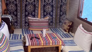 A cozy room with a bed, two sofas, a patterned rug, and a hanging light fixture. - Casa Meryem (Chefchaouen)