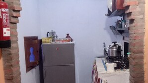 A narrow kitchen with a refrigerator, a stove, and a sink. - Casa Meryem (Chefchaouen)