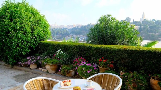 Eine Terrasse mit Korbstühlen, einem Tisch mit Mahlzeit und Topfpflanzen.