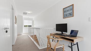 A modern room with a desk, computer, and a chair. There is a sign on the wall and a window with a view.