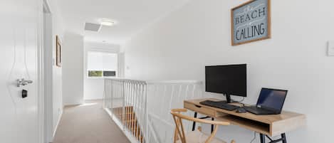 A modern room with a desk, computer, and a chair. There is a sign on the wall and a window with a view.