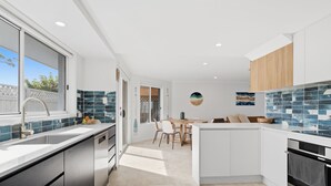 Una cocina moderna con una isla central, comedor y vistas a través de un ventanal.