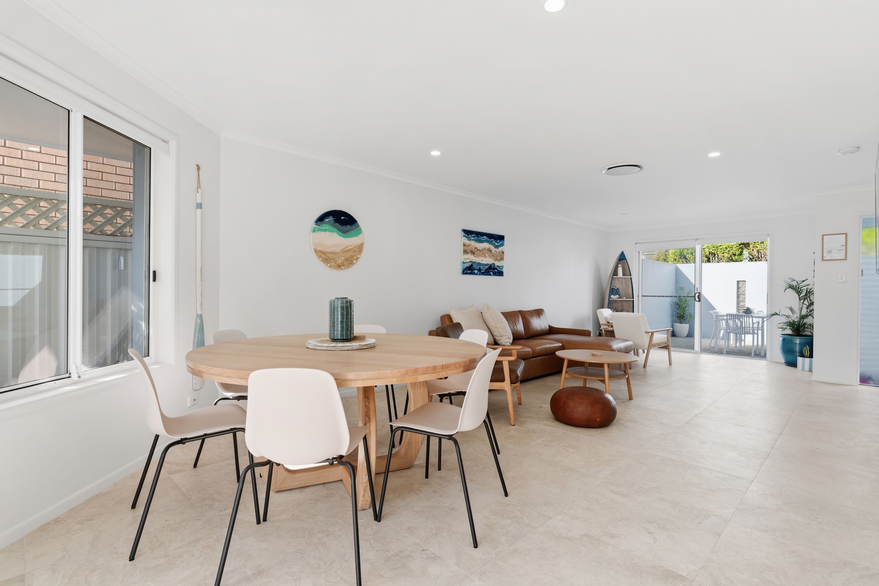 Een modern interieur met een eethoek, een bank en uitzicht door een glazen deur.
