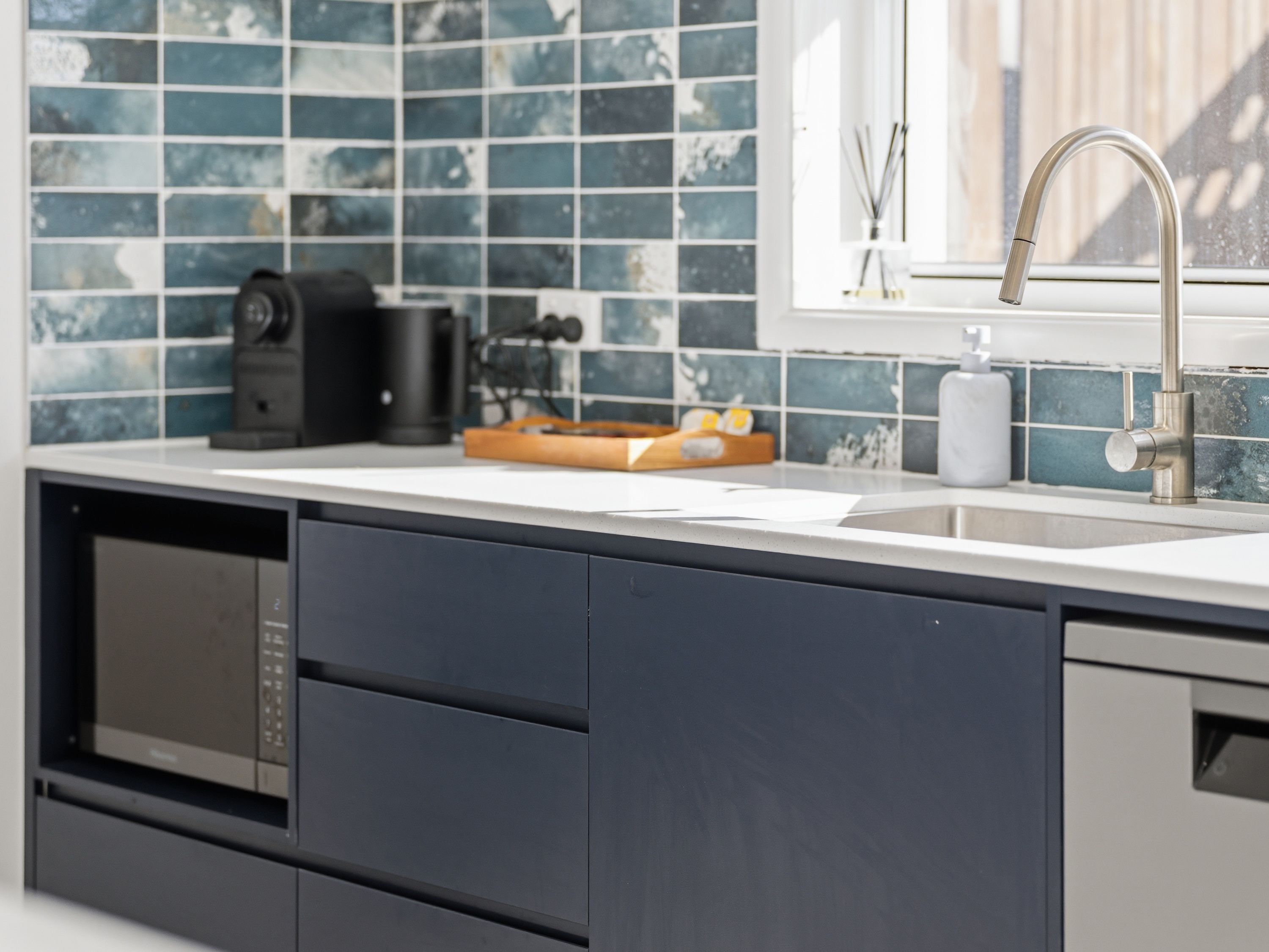 Een moderne keuken met een roestvrijstalen spoelbak, een koffieapparaat en een magnetron.
