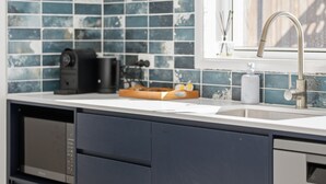 Una cocina moderna con un lavamanos de acero inoxidable, una cafetera y un microondas.