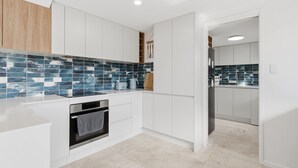 Una cocina moderna con armarios blancos, salpicadero de azulejos y horno empotrado.